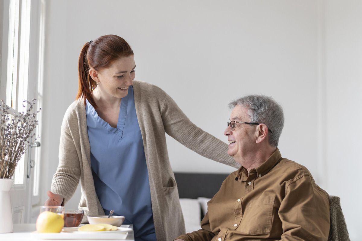 Carer serving a meal to an elderly patient