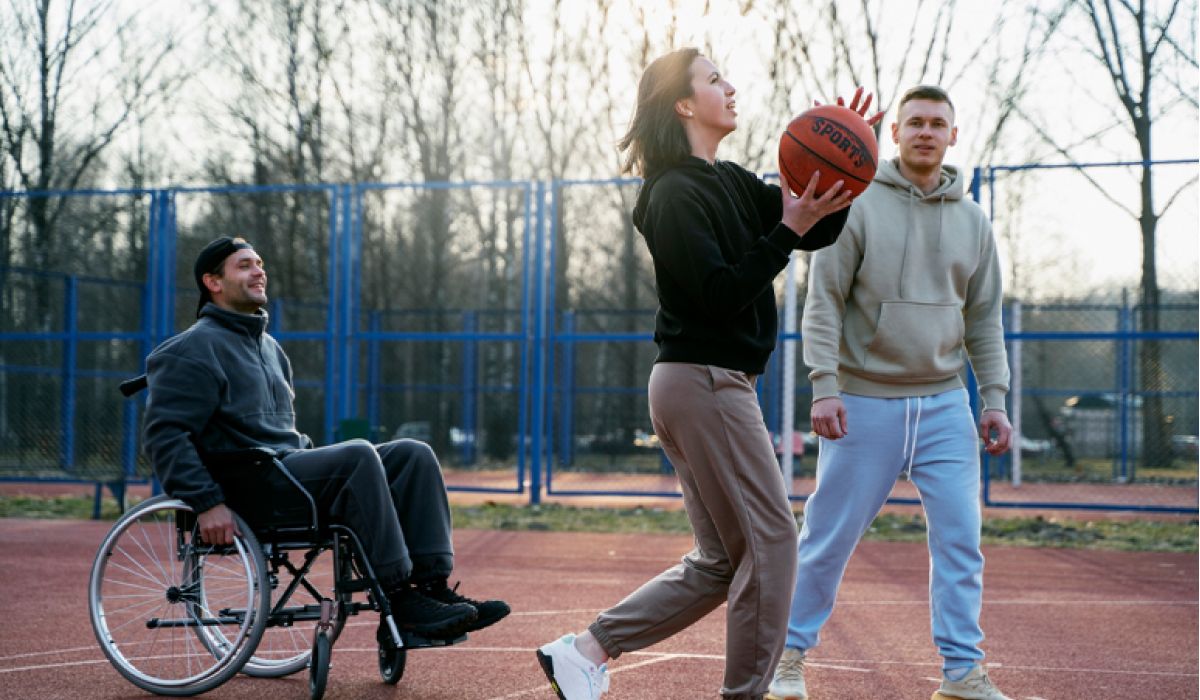 Man in wheelchair socialising with his friends, playing basketball