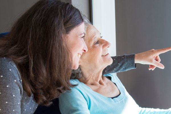 Elder woman and a carer looking through a window